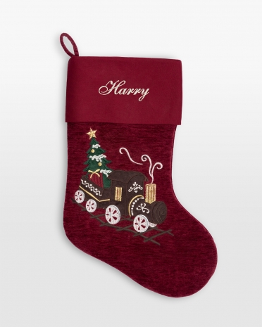 Röd julstrumpa med broderat namn och ett dekorativt tåg