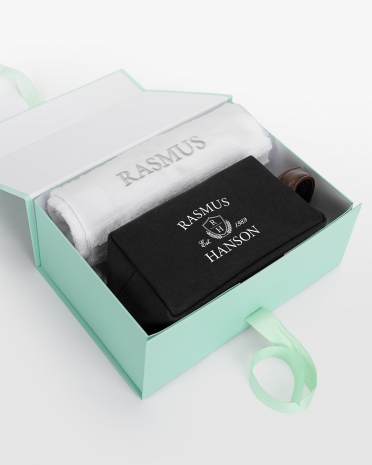 Vitt handdukset (50x70) med silvrig brodyr och svart necessär med namntryck, för elegant personlig stil.