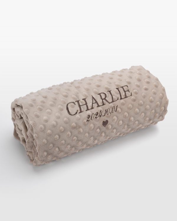 Sandfärgad babyfilt med personlig brun namnbrodyr, perfekt för varm myskomfort och elegant design för din lilla.