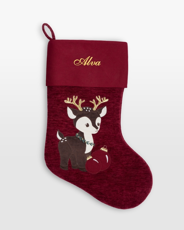 Röd julstrumpa i sammet som broderas med namn och har ett julinspirerat motiv av en ren