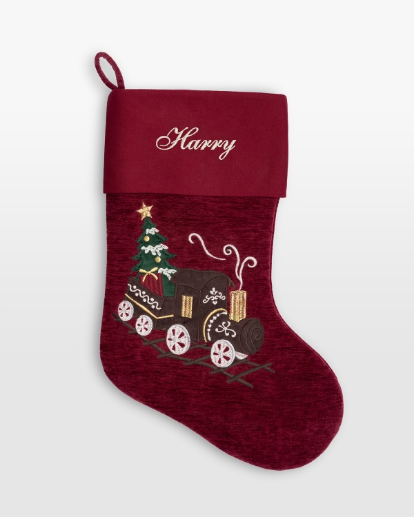 Röd julstrumpa med broderat namn och ett dekorativt tåg