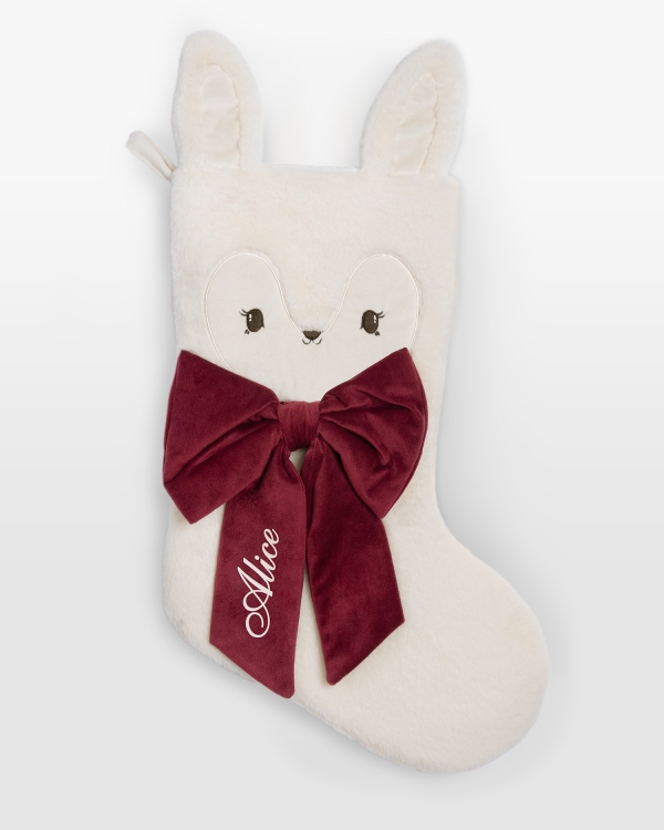 Vit julstrumpa i teddytyg och röd rosett som märks med namn