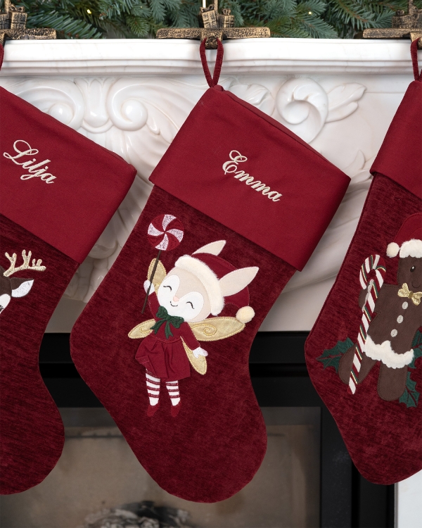 Röd julstrumpa med en älva som kommer broderad med namn