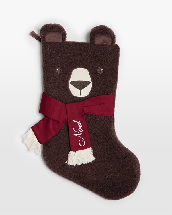 Brun julstrumpa i teddytyg och röd rosett som märks med namn